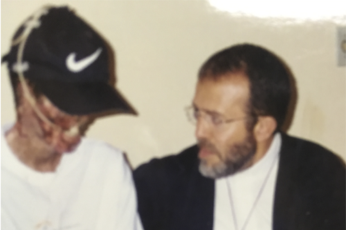 Paulo Roberto com os rosto desfigurado ao lado de Padre João Henrique