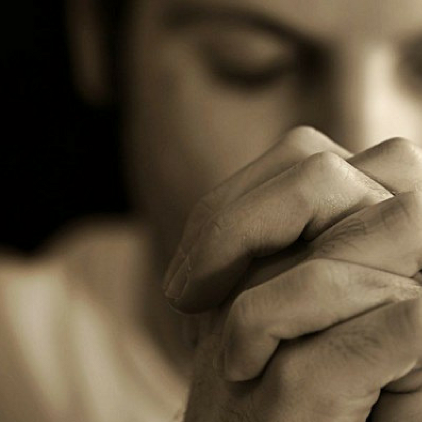 Homem de mãos unidas orando