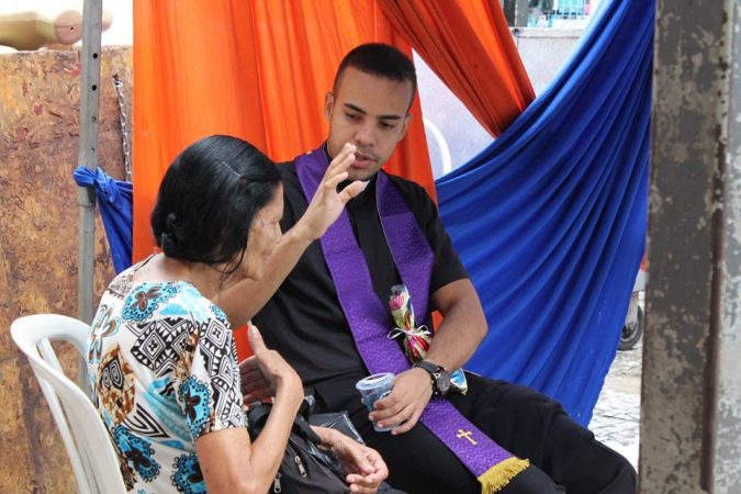 Padre atende uma senhora em confissão