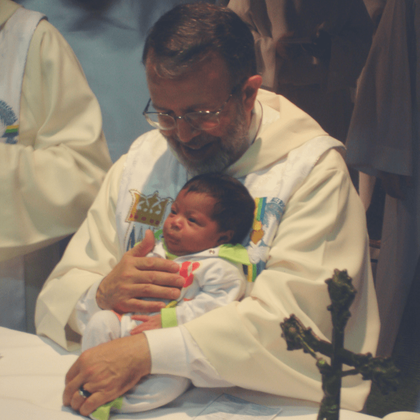 Padre João Henrique segura uma criança