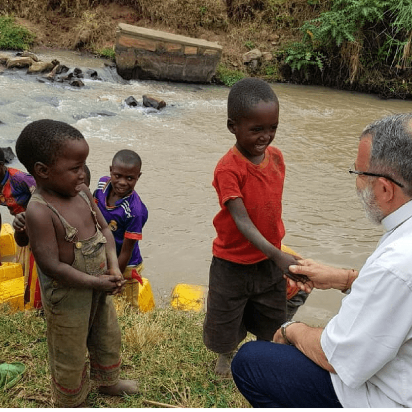 Padre João Henrique brinca com crianças perto do rio.