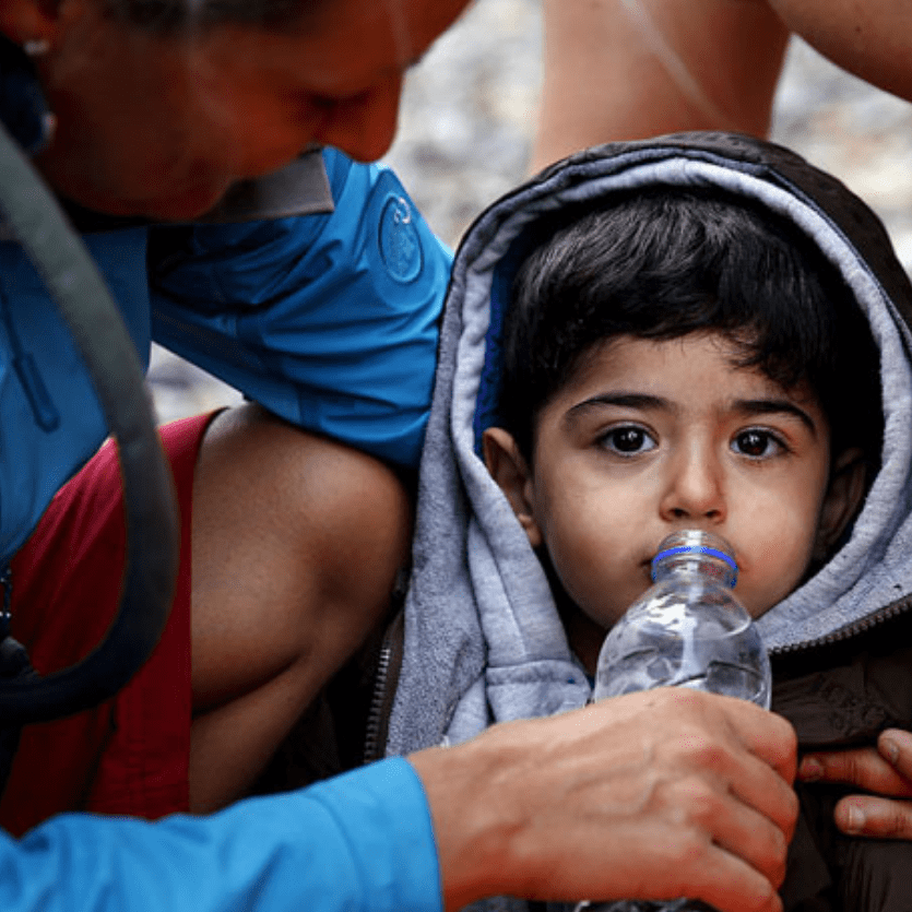 voluntária dá água para criança