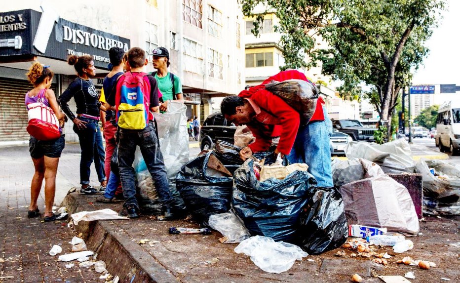 pobre revira lixo a procura de alimento.