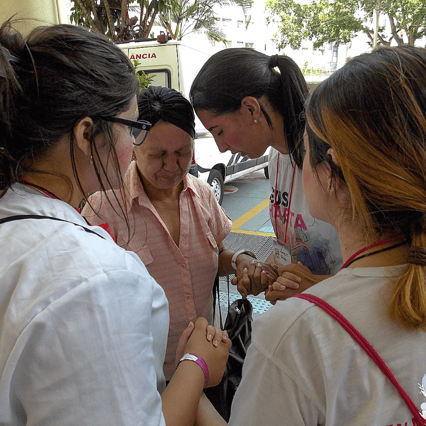 Missionários oram com uma mulher
