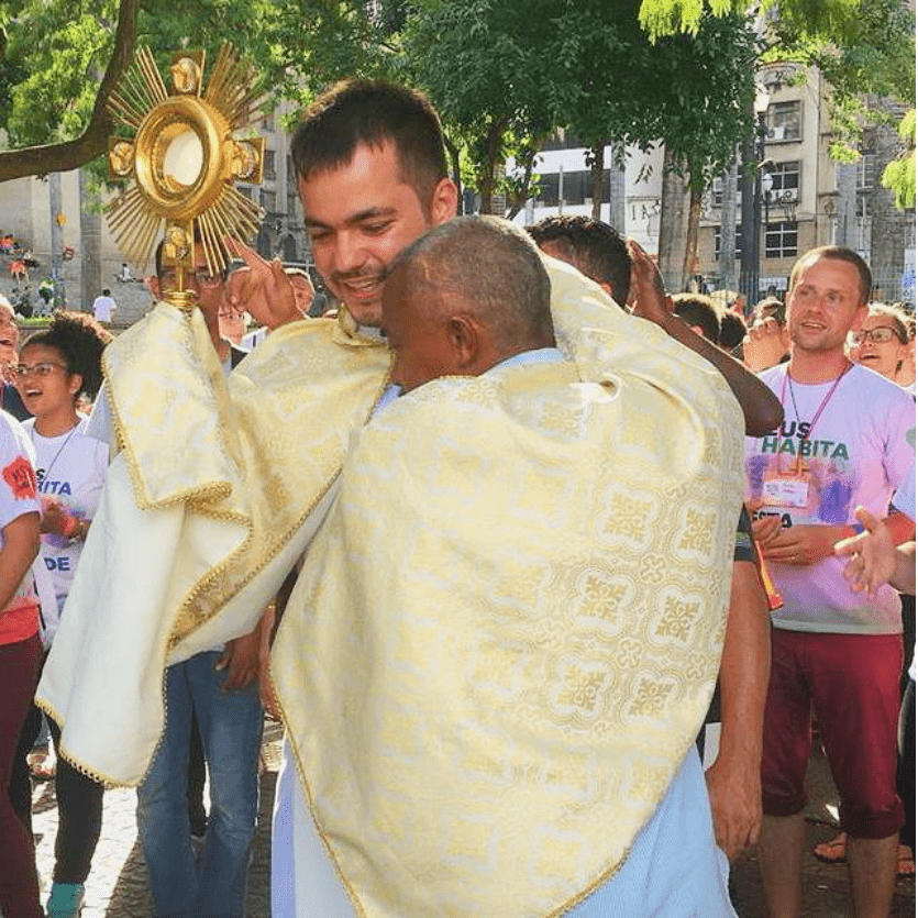 Padre Leandro com o Santíssimo Sacramento é abraça uma pessoa