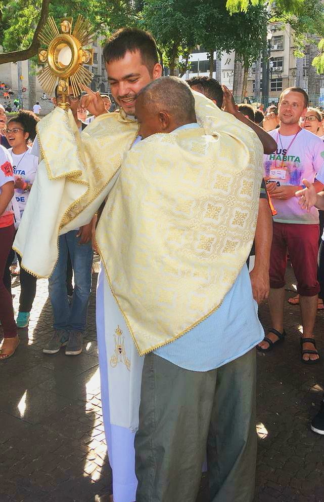 Padre Leandro com o Santíssimo Sacramento é abraça uma pessoa