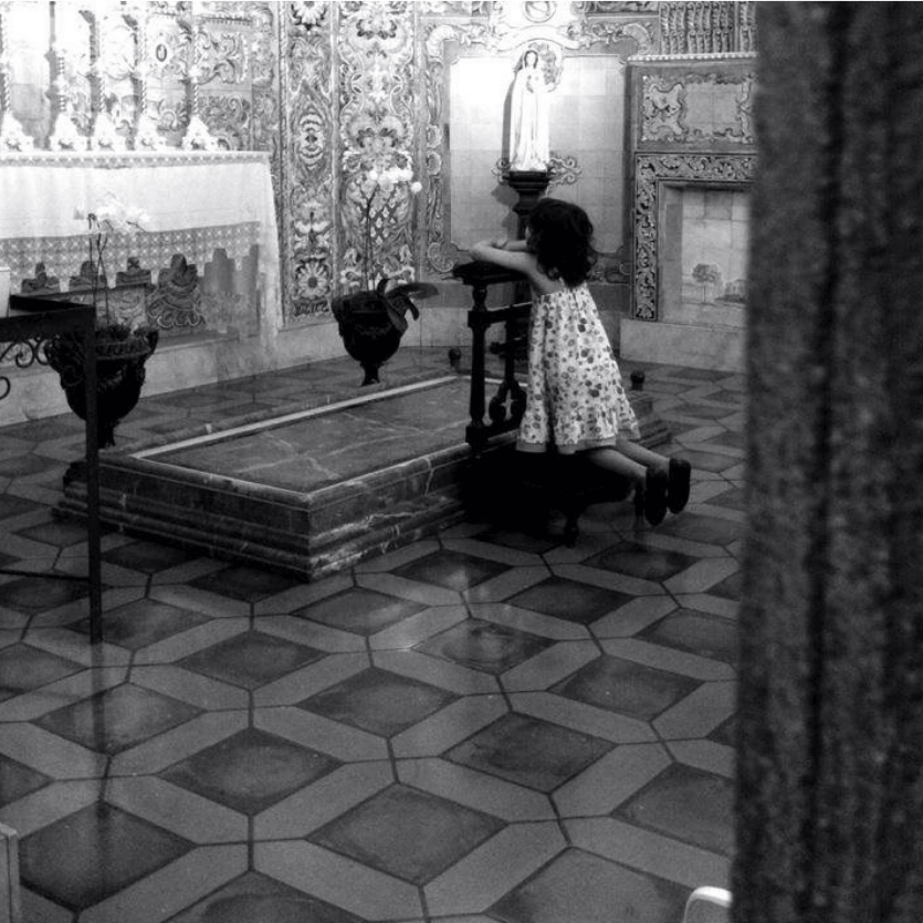 Criança ora de frente ao sacrário.