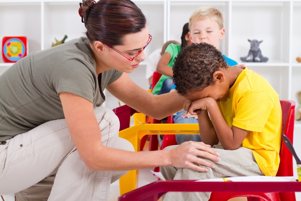 Professora consola um aluno em sala de aula