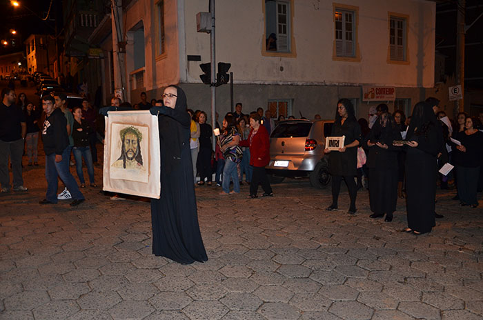 Mulher representando Verônica, canta e mostra um tecido com o face de Cristo.