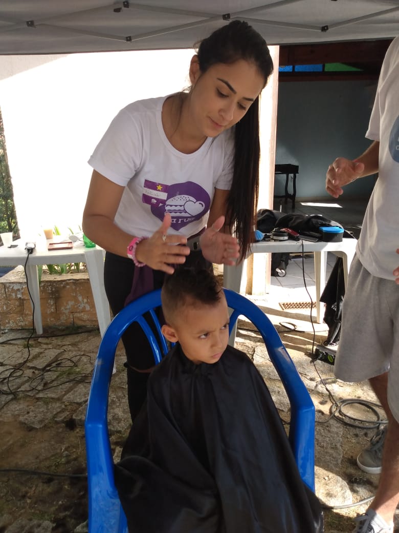 Voluntária realiza corte de cabelo em criança