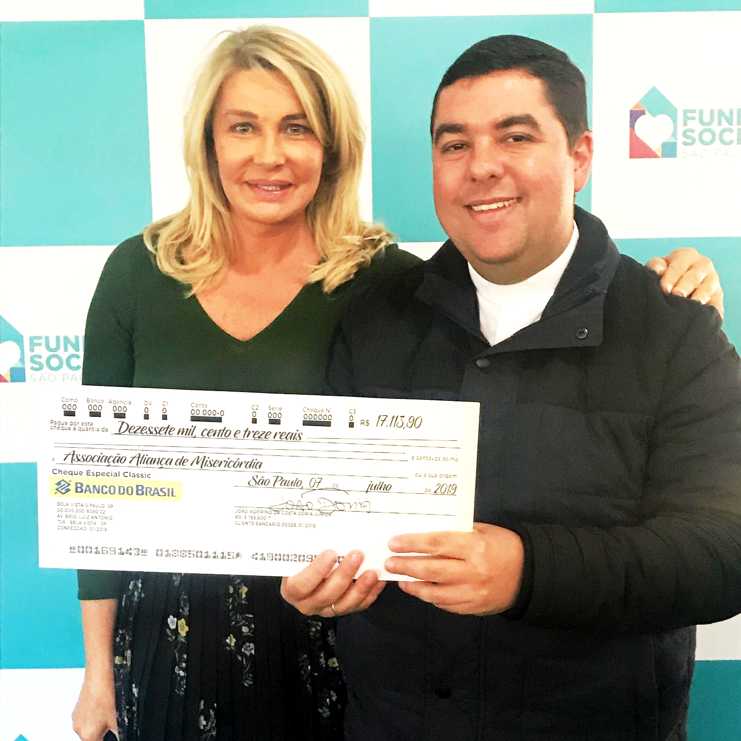 Bia Doria entrega o cheque nas mãos de Pae. Custódio.