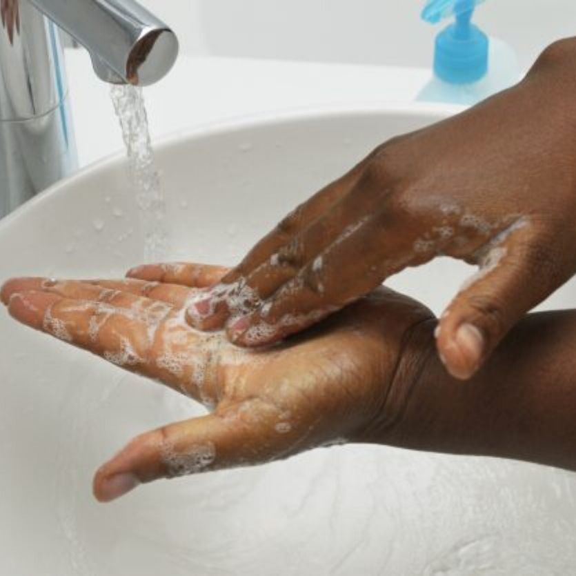 detalhas das mãos sendo lavadas com sabão numa pia branca