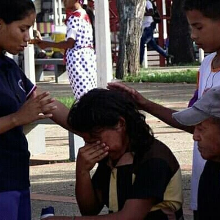 Três missionárias rezam por mulher que chora.