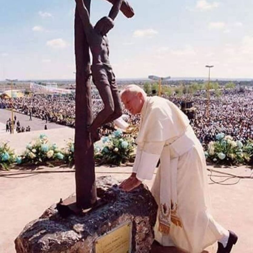 São João Paulo II ajoelhado em frente ao crucifixo.
