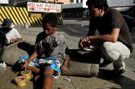 Criança venezuelana recebe alimento de voluntário