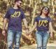 Casal anda de mãos dadas por um caminho de árvores