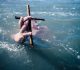 Homem submerso segura uma cruz sobre as águas